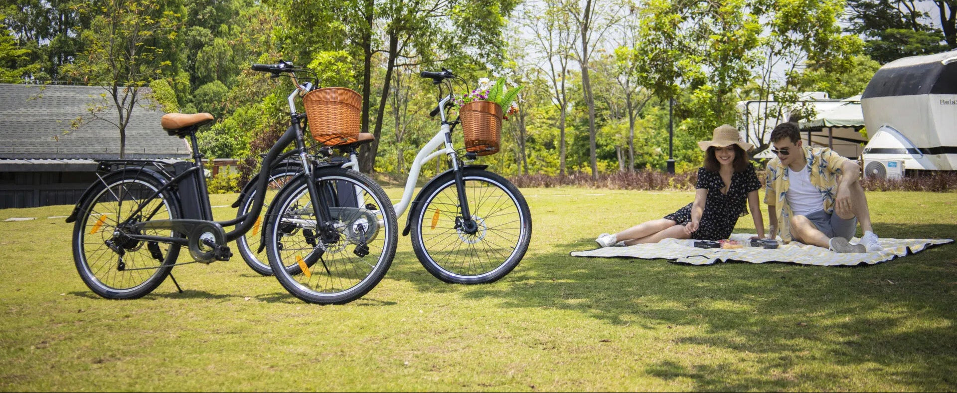 Young couple sitting on lawn having a picnic in caravan park with DYU Electric Bikes in foreground