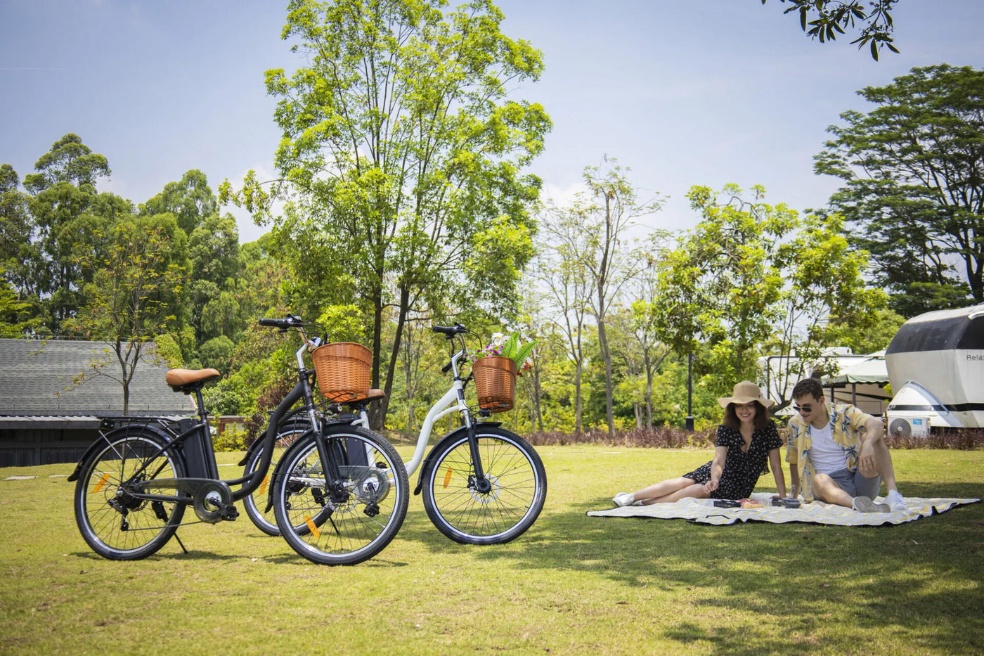 Young couple sitting on lawn having a picnic in caravan park with DYU Electric Bikes in foreground